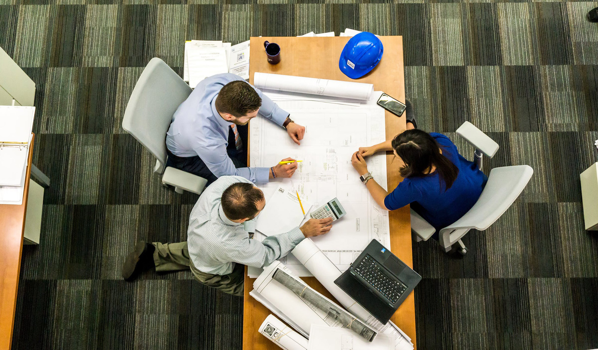 mesa de trabalho com três pessoas a trabalhar a coordenação e os projetos de especialidade